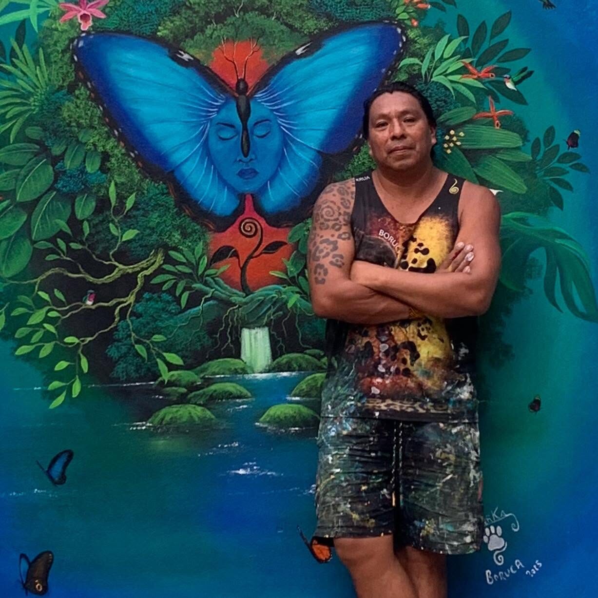 Kamel González Rojas standing in front of his blue morpho butterfly mural